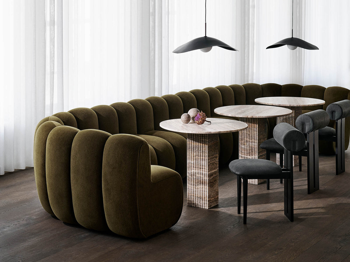 Sofa NORR11 Jagger Dining w oliwkowym welurze w restauracji ze stolikami Soho i lampami Fuji