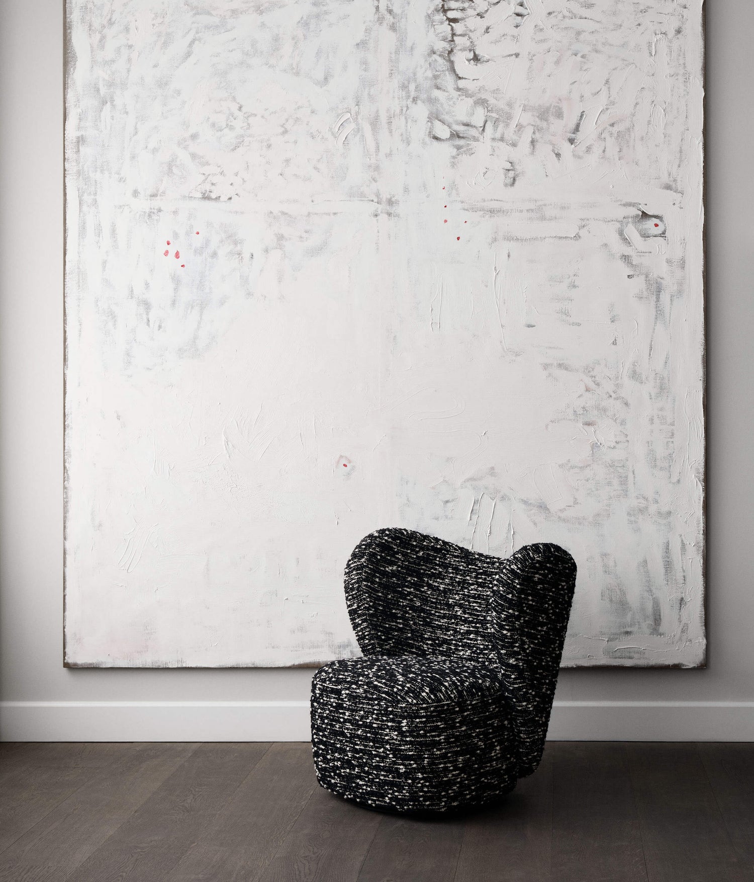 Black textured chair in front of a large abstract painting on a gray wall.