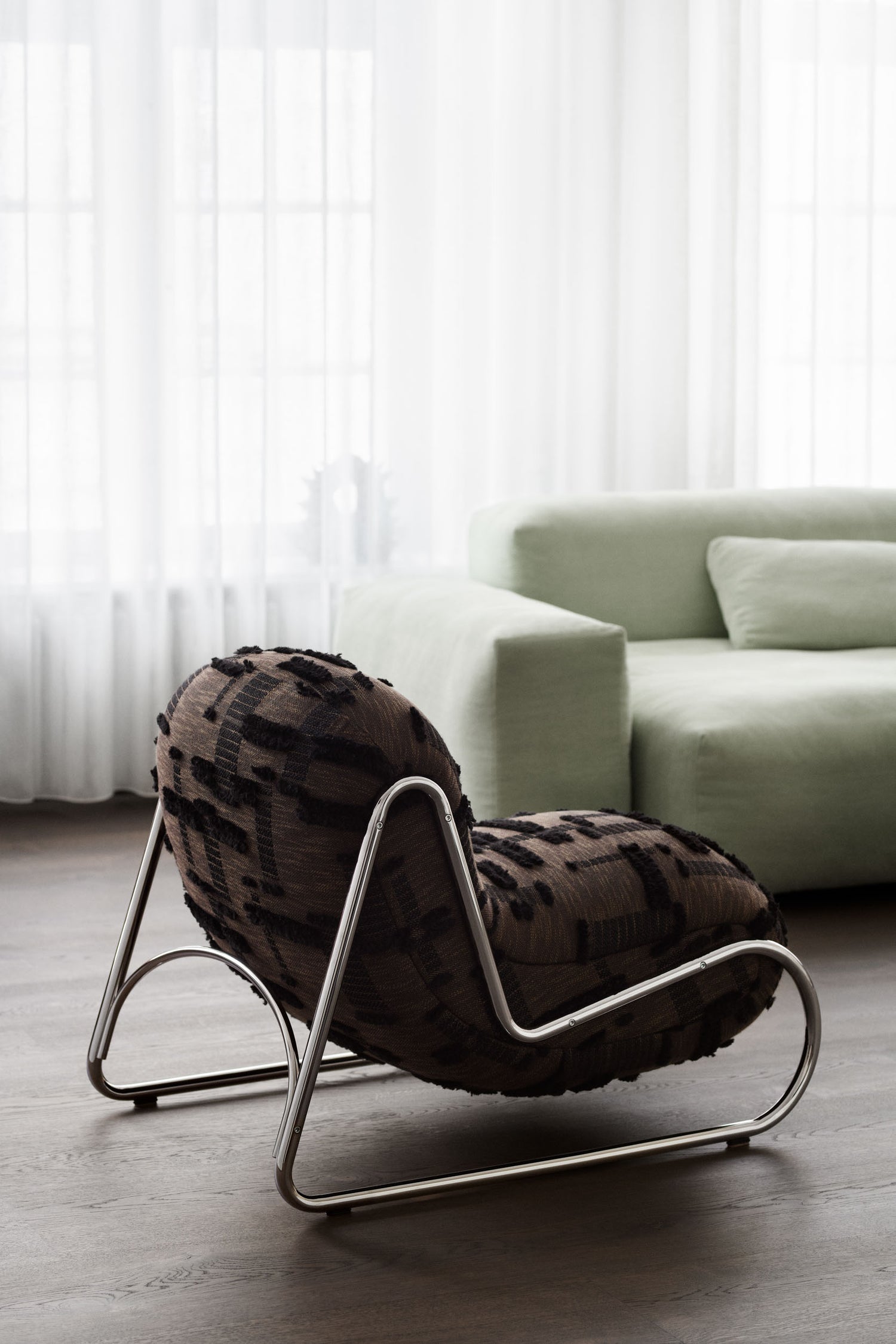 Boho Chair with brown textured upholstery in front of a mint colored sofa