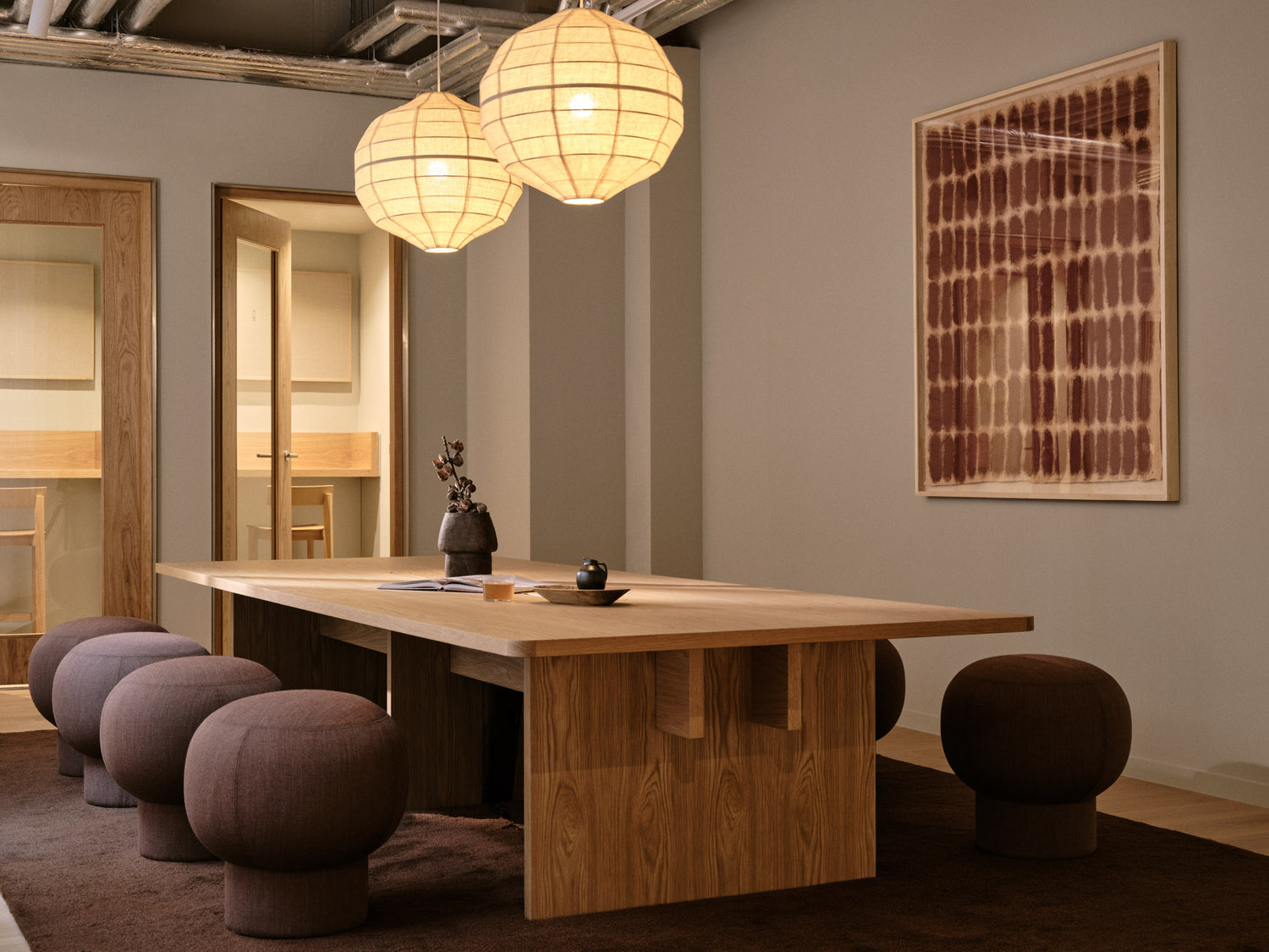 Modern interior with wooden table and Liège poufs in a room with neutral walls and decor.