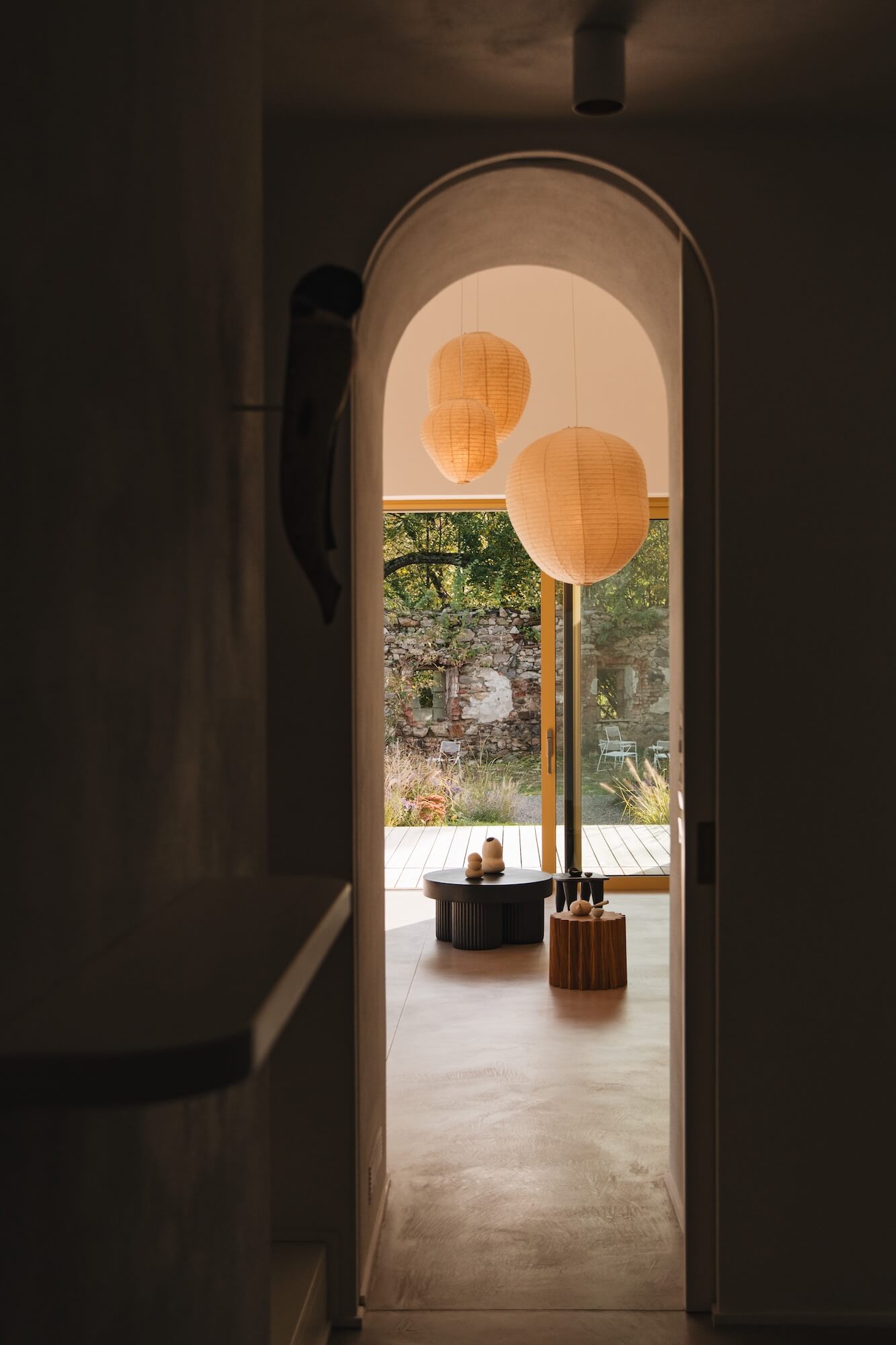 Archway leading to a room with decorative lamps, Gear round coffee table and a garden view.